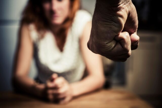 Man's fist as culprit with woman in background looking down