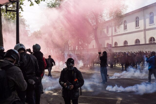 People in protest with tear gas spraying everywhere