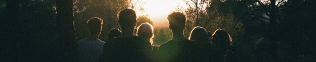 Young people peacefully looking at the sunset in forest