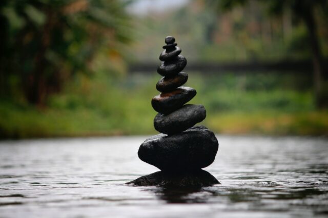 Rocks standing on top of each other in pond representing cooperation balance