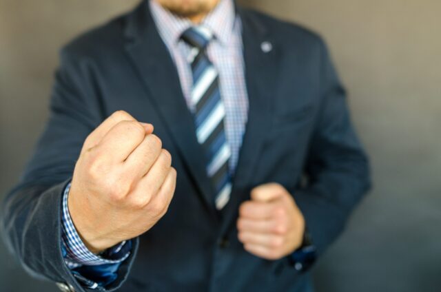 Aggressive man in suit pointing fist at screen