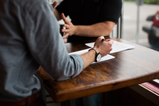 Men talking writing and being agreeable at workplace table