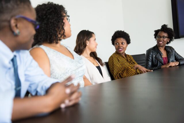 A table of women of color discussing the cost of workplace conflict