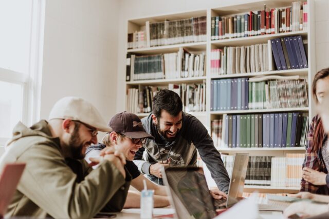 Three men laughing at computer engaged in work