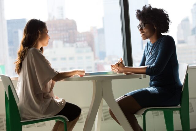 two women sitting beside window in positive communication