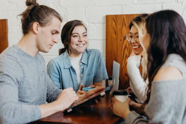 Four employees in work engagement smiling at wooden table