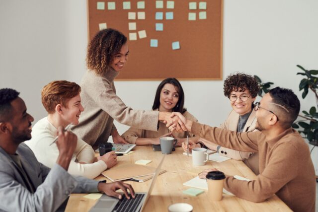 Two employees building rapport by shaking hands in a group at work