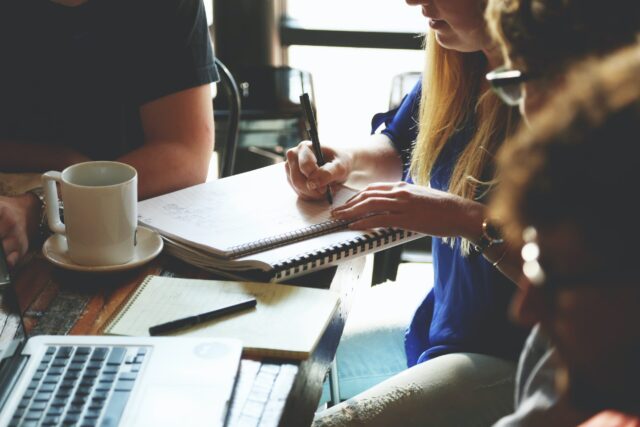 Leader writing down notes in work meeting about managing employee conflict