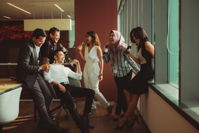 A diverse group of immigrants laughing with each other drinking sodas