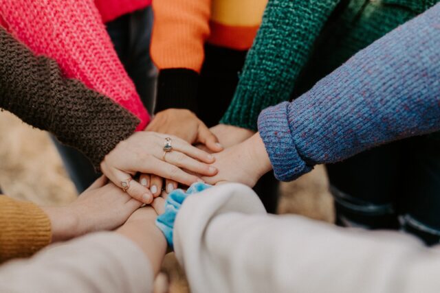 Employees putting hands in the middle of a circle representing conflict transformation