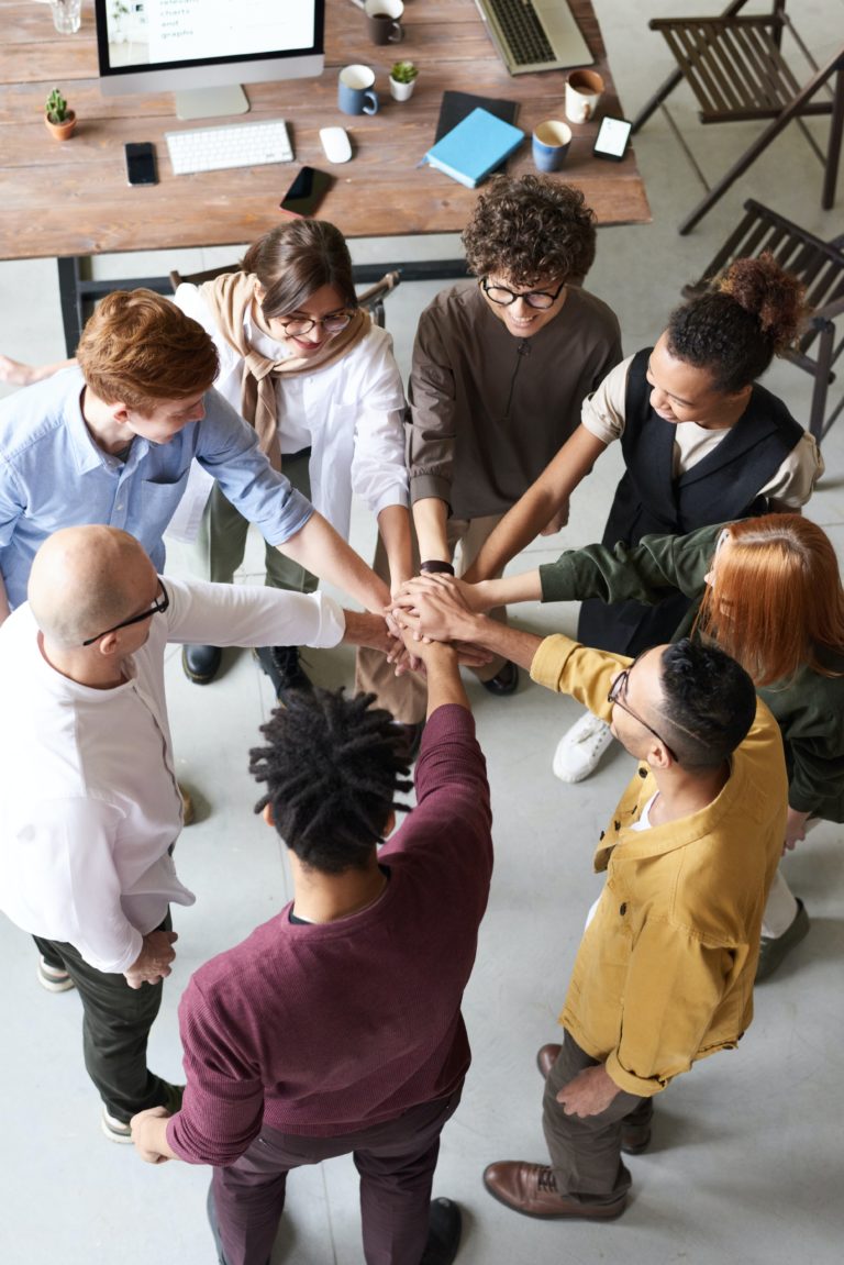 Employees Building Team Communication Skills Employees placing their hands together during a workplace communication exercise