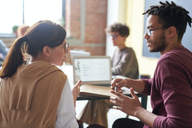 two employees at work talking about factors that affect conflict in the workplace