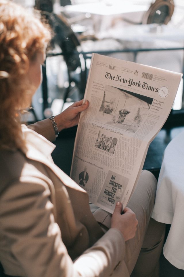 Woman reading the news via newspaper