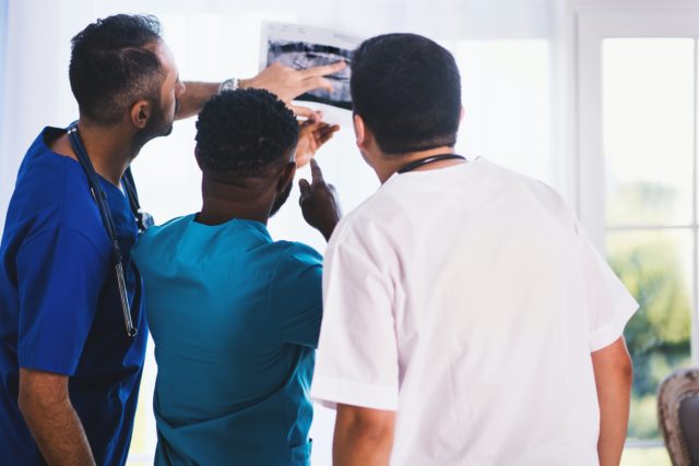 three health employees in team communication looking at X-ray