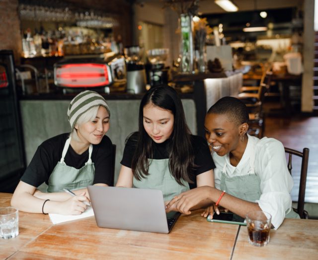 Three employees discussing at computer the keys to a peaceful organization