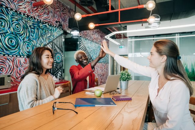 Three happy coworkers at work in intergroup contact like the nature of prejudice