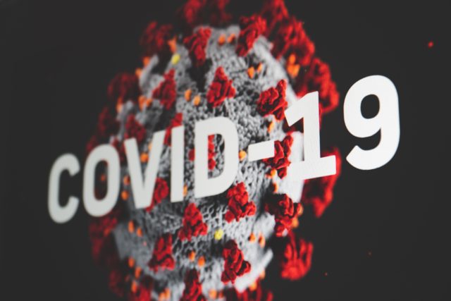 Black background with germ that reads 'covid-19,' representing Effects of Covid-19 on Identity