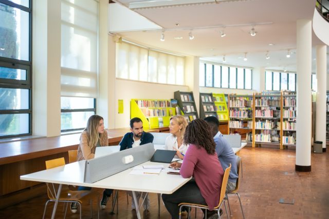 People meeting in a desk inside a library