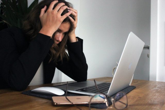 Woman at workplace appears frustrated with head in hands