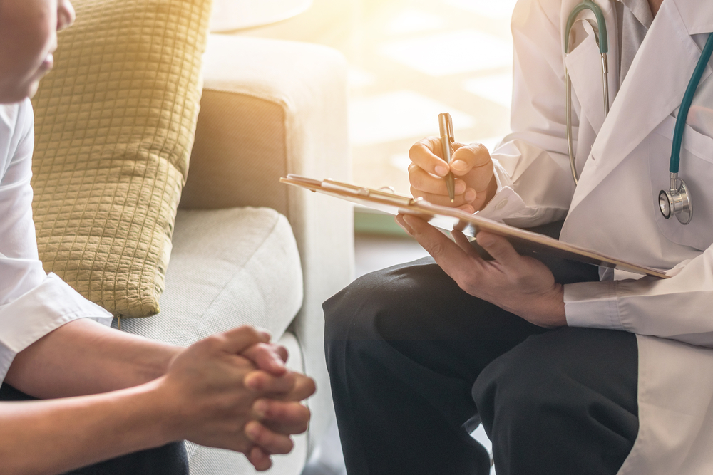 Photo of two people sitting and talking one takes notes