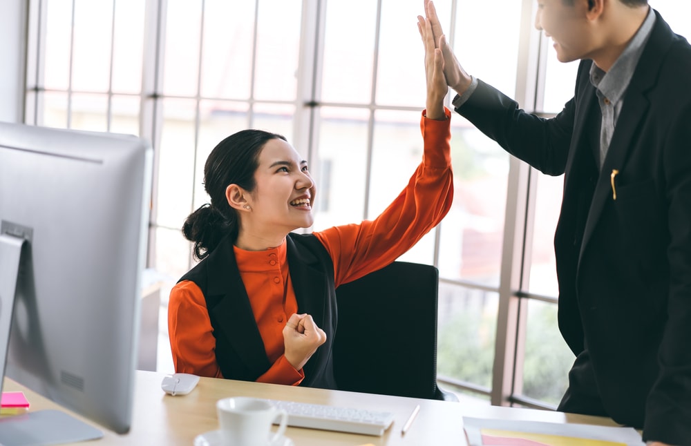 Woman high five-ing a workplace teammate.