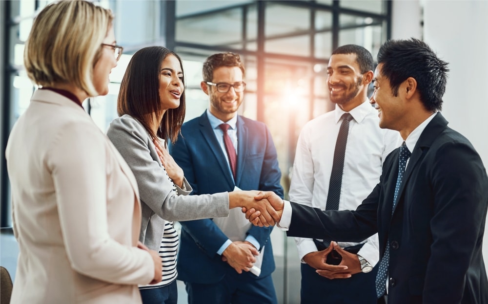 Group, business people and shaking hands for welcome, introduction or meeting in office. Handshake, smile and team with deal for collaboration, agreement or thank you for b2b partnership opportunity