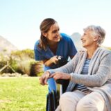 Nurse talking to an elderly patient outside in sunny weather