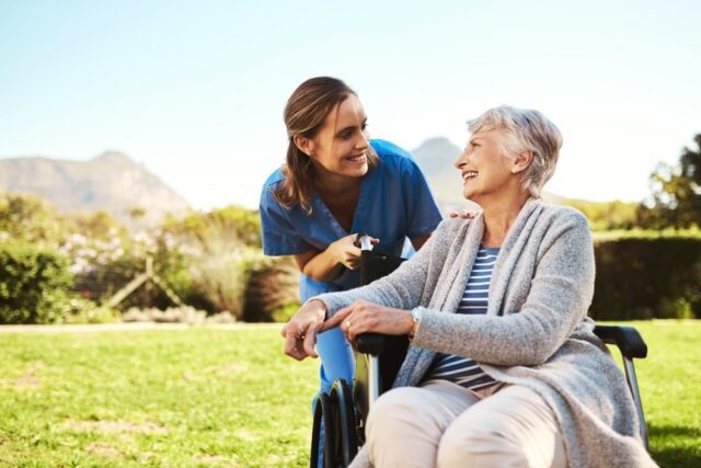 Nurse talking to an elderly patient outside in sunny weather