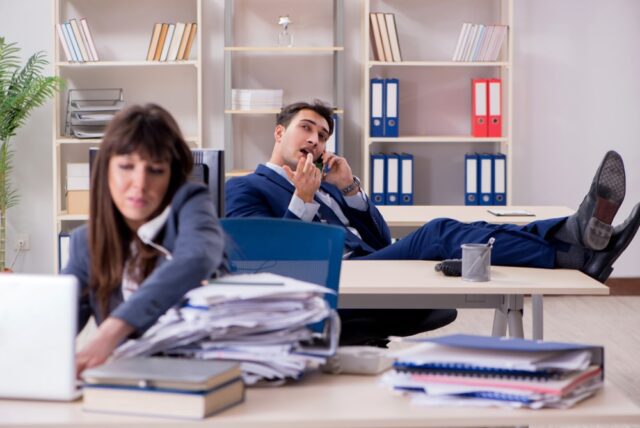 Busy businesswoman overwhelmed with work while her business partner is being lazy by talking on the phone