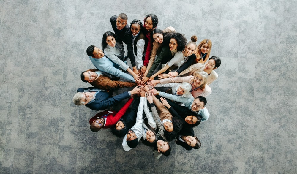 Picture shot from above capturing many employees in a huddle.